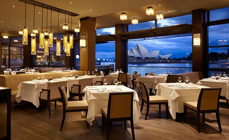 تصویری از رستوران در هتل است که در آن از میز و صندلی های زیبایی با فاصله مناسبی از هم قرار دارند.