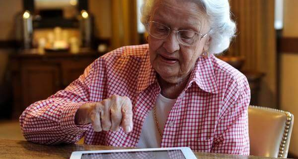 تصویری از یک زن سالمند در حال کار با تبلت جهت مدیریت خانه هوشمند برای سالمندان
