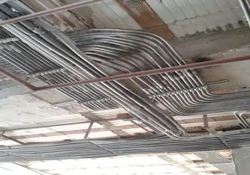 تصویر لوله های برق در سقف کاذب یک ساختمان را نشان می دهد.