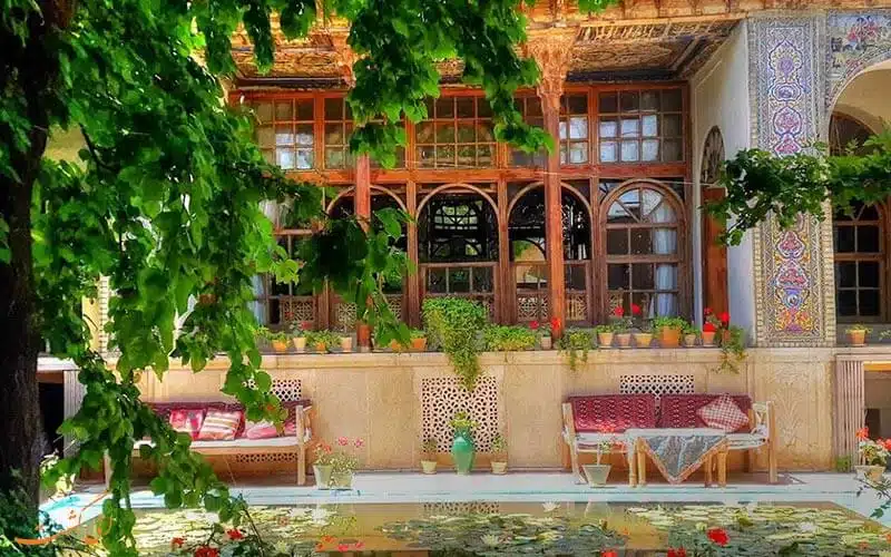 تصویری از یک خانه قدیمی در شیراز است که درب و پنجرره های چوبی به همراه یک حیاط بزرگ دارد.