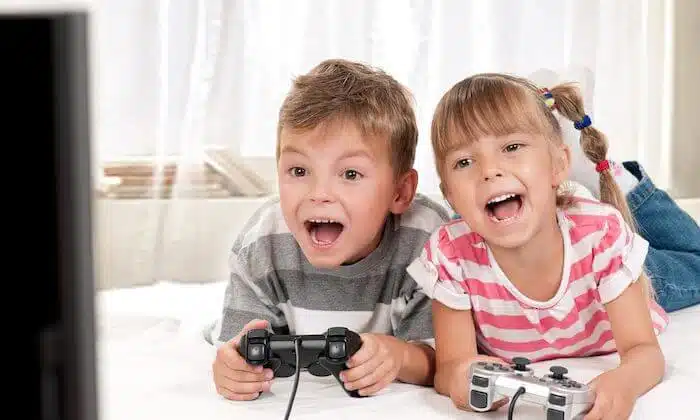 تصویری از یک دختر بچه و پسر بچه می باشد که در دست هر یک از آن ها یک دسته بازی کامپیوتری است.
