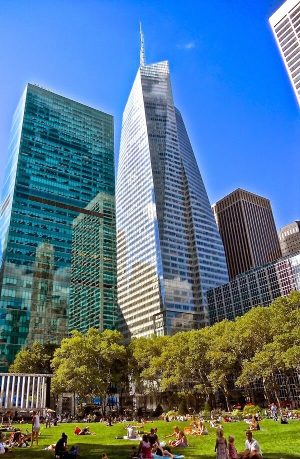  تصویری از ساختمان بانک آمریکار در نیویورک را نشان می دهد که در اطراف آن درختان و گیاهان زیادی قرار دارد.